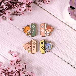May include: Four enamel pins featuring cartoon animal characters holding a Nintendo Switch console. The pins are in different colors: green, orange, pink, and yellow.