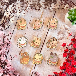 Pode incluir: Nove pinos de esmalte com renas de desenho animado com decorações de Natal vermelhas e brancas. Os pinos estão em uma superfície de madeira com flores vermelhas e brancas.