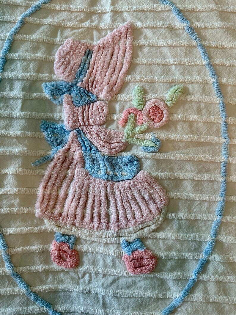 May include: A vintage, white, crocheted throw blanket with a pink and blue embroidered design of a little girl holding a flower.