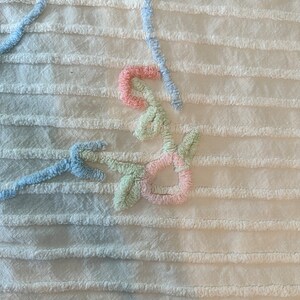 May include: A white crocheted throw blanket with a floral design in shades of blue, green, and pink.
