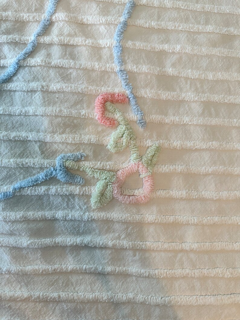 May include: A white crocheted throw blanket with a floral design in shades of blue, green, and pink.