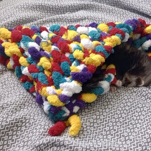 a cute hand knitted snuggle cone for small animals / ferrets hand knitted in soft thick chunky yarn in "balloon fiesta" (red, blue, yellow, white and purple) great for burrowing and snuggling