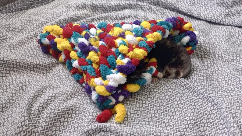 a cute hand knitted snuggle cone for small animals / ferrets hand knitted in soft thick chunky yarn in "balloon fiesta" (red, blue, yellow, white and purple) great for burrowing and snuggling
