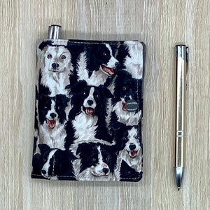 May include: A patterned fabric wallet with a design of black and white Border Collie dog faces. A silver pen is placed to the right of the wallet. The wallet has a silver metal closure.