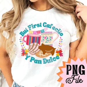 以下が含まれることがあります： カラフルなマグカップ、パン・ドゥルセ、そして「But First Cafe y Pan Dulce」というテキストが描かれたグラフィックデザインが施された白いTシャツです。