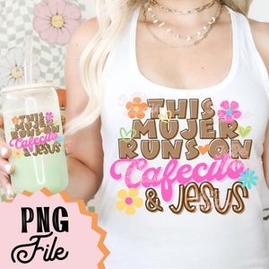 以下が含まれることがあります： 白いタンクトップに、茶色とピンクの文字で「This Mujer Runs On Cafecito & Jesus」と書かれています。文字の周りはハートと花で囲まれています。
