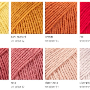 Pode incluir: Uma cole&ccedil;&atilde;o de novelos de l&atilde; em v&aacute;rias cores, incluindo cinza p&eacute;rola claro, amarelo lim&atilde;o, mostarda escura, laranja, vermelho e vermelho vinho. Cada novelo &eacute; rotulado com o nome da cor e um identificador &uacute;nico.