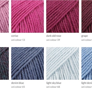 Pode incluir: Uma cole&ccedil;&atilde;o de novelos de l&atilde; em v&aacute;rias cores, incluindo rosa, roxo e azul. Cada novelo &eacute; rotulado com o seu nome de cor e um n&uacute;mero de cor uni correspondente. As cores variam de tons claros a escuros.