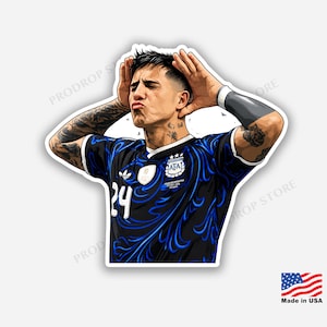 Puede incluir: Una pegatina troquelada que muestra a un futbolista con tatuajes en ambos brazos, vistiendo una camiseta negra con patrones de llamas azules, el número 24 y un escudo de la AFA. Tiene las manos detrás de las orejas, ojos cerrados y labios fruncidos.
