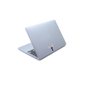 May include: A silver laptop computer with a sticker of a person with their arms raised in the air.