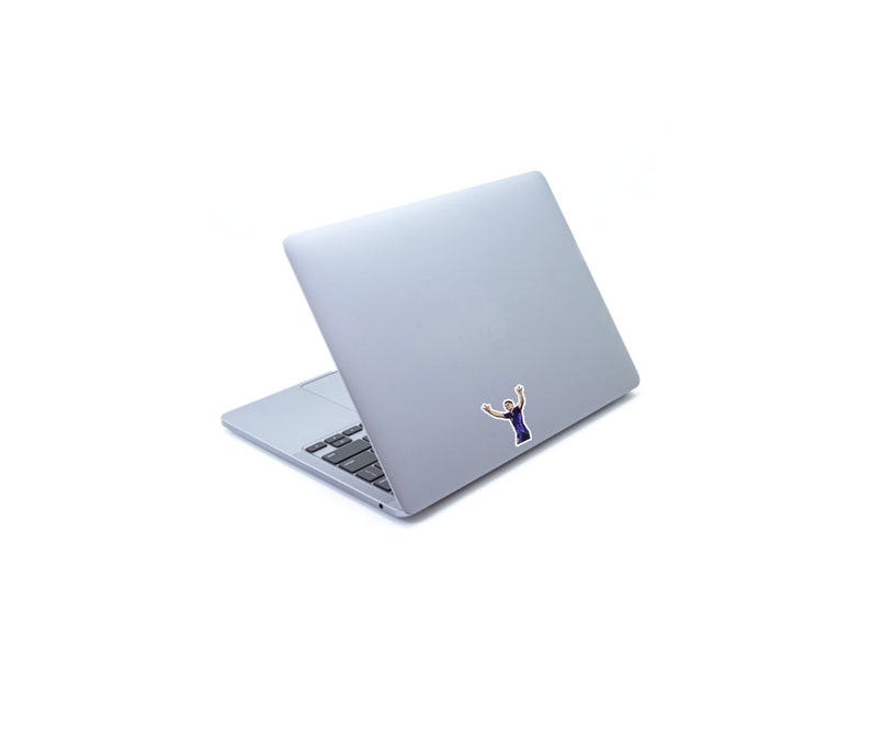 May include: A silver laptop computer with a sticker of a person with their arms raised in the air.