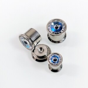 May include: Set of four silver ear gauges with blue and clear crystal accents. The gauges are in different sizes.