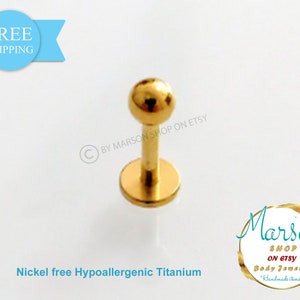 Puede incluir: Joyería corporal de titanio de color dorado con una pequeña bola en la parte superior. La joyería es libre de níquel e hipoalergénica.  "BY MARSON SHOP ON ETSY" está impreso en el fondo blanco.
