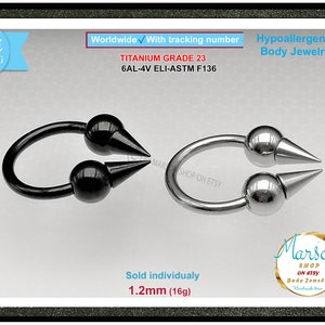 Op de afbeelding: Twee titanium lichaamsieraden met spikes. Eén is zwart en de andere is zilver. Beide zijn 1,2 mm (16 g) groot. De tekst op de afbeelding luidt "Titanium Grade 23 6AL-4V ELI-ASTM F136".