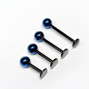 Peut inclure: Quatre clous de labret noirs avec des billes bleues irisées. Les clous sont disposés en rangée du plus grand au plus petit.