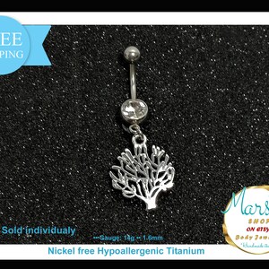 Puede incluir: Un piercing para el ombligo de color plateado con una gema transparente y un dije en forma de árbol. La joya está hecha de titanio hipoalergénico sin níquel. El calibre es de 1,6 mm. También se ve el texto "Sold individually".