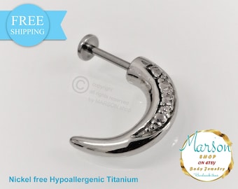 May include: Silver titanium body jewelry with a curved, textured design. The jewelry is nickel free and hypoallergenic.