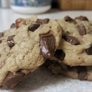 May include: A stack of three chocolate chip cookies with large chocolate chunks. The cookies are golden brown and have a slightly crispy texture.