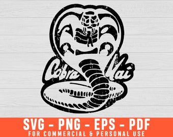 May include: A black graphic illustration of a cobra snake with its hood flared, featuring a distressed texture. The text Cobra Kai is written in a stylised font across the centre of the snake. The design is presented on a white wood background.
