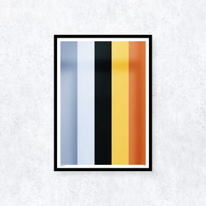 May include: A framed art print featuring vertical stripes in shades of gray, white, black, yellow, and orange. The artwork is displayed against a textured white wall, creating a modern and minimalist aesthetic. The print is enclosed in a black frame.