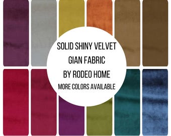May include: A collection of twelve rectangular fabric swatches in various colors including purple, gray, yellow, orange, brown, red, magenta, olive green, teal, and blue. The text reads SOLID SHINY VELVET GIAN FABRIC BY RODEO HOME MORE COLORS AVAILABLE.