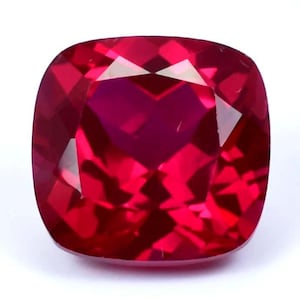 Peut inclure: Une pierre précieuse rouge foncé de taille coussin. La pierre précieuse est facetée et a un haut poli.