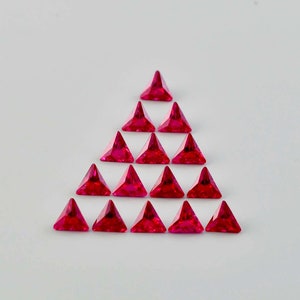 May include: A triangular arrangement of 18 red triangular gemstones. The gemstones are arranged in a pyramid shape, with the largest gemstone at the top and the smallest gemstones at the bottom.