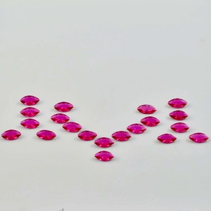 Puede incluir: Una dispersión de diamantes de imitación rosados facetados en forma de marquesa sobre un fondo blanco.