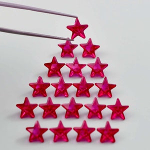 Op de afbeelding: Een roze stervormige kerstboom gemaakt van strass. De boom is gemaakt van 18 sterren, met de grootste ster bovenaan en de kleinste sterren onderaan.