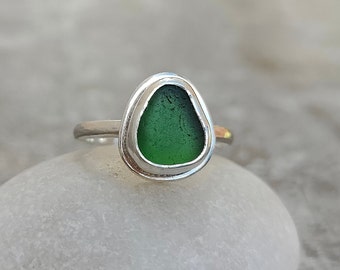 Op de afbeelding: Een zilveren ring met een groene zeeglassteen in een bezel-setting.