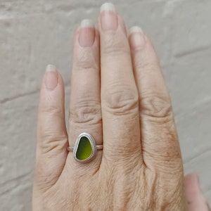 May include: A silver ring with a green sea glass stone set in the center.