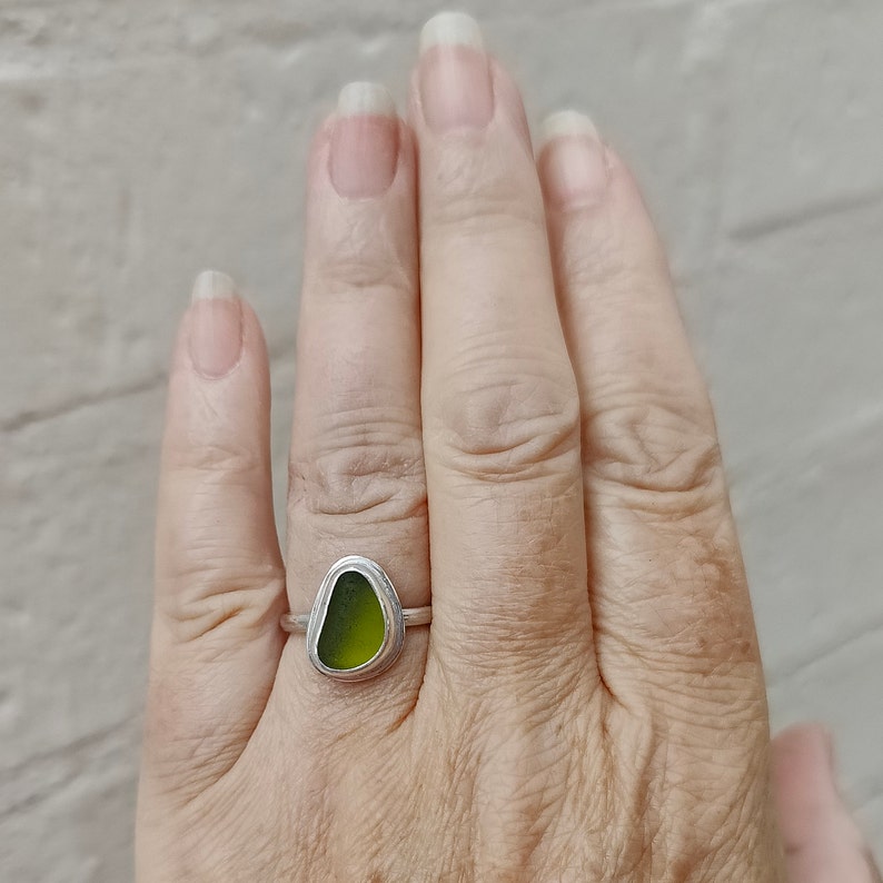 May include: A silver ring with a green sea glass stone set in the center.