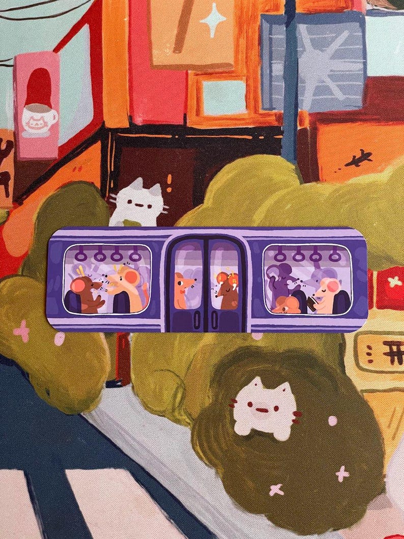 May include: A purple sticker featuring a cartoon train with passengers. The train has two doors and windows showing various animals. A white cat sticker is in the foreground. The background has a colorful cityscape.