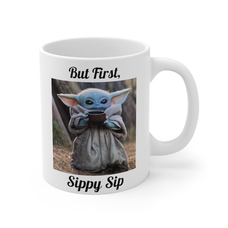 K&ouml;nnte beinhalten: Eine wei&szlig;e Keramiktasse mit einem Schwarzwei&szlig;bild eines Charakters aus dem Star Wars-Franchise, der aus einer Sch&uuml;ssel trinkt. Der Text "But First, Sippy Sip" ist auf die Tasse gedruckt.