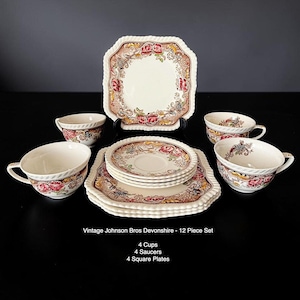 May include: A 12-piece vintage Johnson Bros Devonshire tea set. The set includes four cups, four saucers, and four square plates. Each piece features a floral design with pink, red, and yellow accents on a cream background. The plates have a scalloped edge.