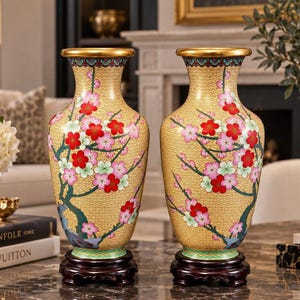 Pode incluir: Um par de vasos amarelos a combinar com um padrão geométrico dourado detalhado na superfície. Cada vaso é decorado com flores vermelhas, rosas e verde-claras vibrantes em ramos escuros e assenta numa base de madeira escura.