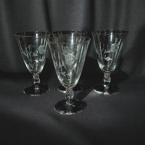 May include: A white ceramic mug with a black handle and the text "But First, Coffee" in a black, bold font. The mug is sitting on a white surface.