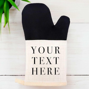 Op de afbeelding: Zwart-witte ovenwant met de tekst "YOUR TEXT HERE" gedrukt op het witte gedeelte.