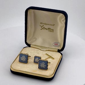 May include: A pair of square Wedgwood by Stratton cufflinks featuring a blue jasperware inlay with a white relief design of a figure on horseback. The cufflinks are presented in a navy blue hinged box with cream satin lining and a British flag sticker.