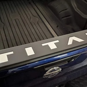 May include: A blue pickup truck bed with a black bed liner and a white "TITAN" logo.