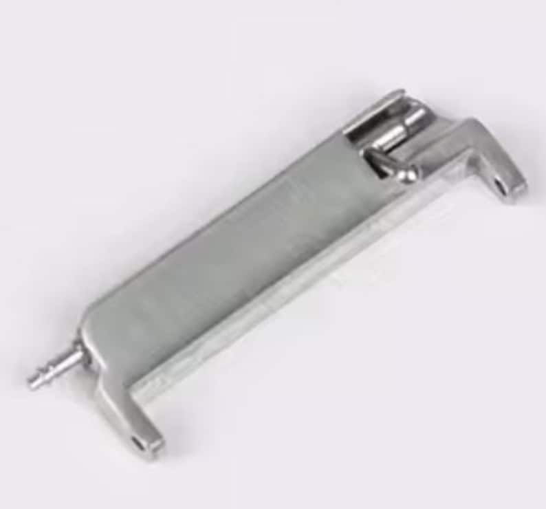 May include: A silver metal tool with a handle and a lever. The tool has a small hole on one end and a small metal pin on the other end.