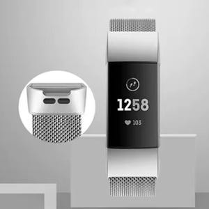 Könnte beinhalten: Ein silbernes Metallband für einen Fitness-Tracker mit einem schwarzen Bildschirm, der 1258 und eine Herzfrequenz von 103 anzeigt. Das Band hat einen Verschluss.