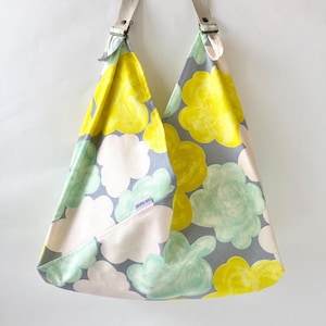 May include: A gray, yellow, and green floral print tote bag with adjustable straps. The bag has a small white label with the text "goods on" printed on it.