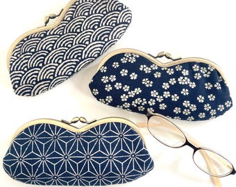 May include: Three elongated fabric eyeglass cases with brass-toned metal kiss-lock closures. Each case features a distinct dark blue and white pattern: one with concentric waves, one with small floral motifs, and one with a geometric star design.