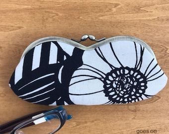 Estuche para gafas blanco y negro con cierre de broche y un llamativo estampado floral grande.