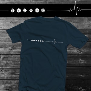 Puede incluir: Una camiseta azul oscuro con un gráfico blanco de una línea de latido del corazón con siete dados en fila.