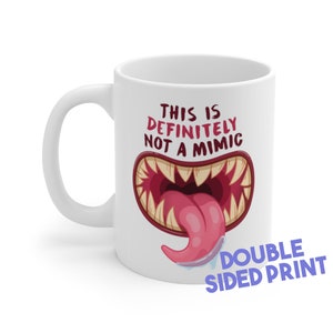 Könnte beinhalten: Weiße Keramik-Kaffeetasse mit einem roten und weißen Cartoon-Monstermaul mit dem Text "This is definitely not a mimic" und den Worten "Double Sided Print" in lila Schrift.