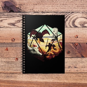 May include: A black spiral notebook with a colorful illustration of a fantasy scene inside a 20-sided die. The scene includes a dragon, a warrior, a snake, and a skull.