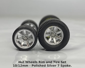 Peut inclure: Un ensemble de quatre jantes et pneus Hot Wheels à 7 rayons en argent poli de 10/12 mm. Les pneus sont noirs et les jantes sont argentées.