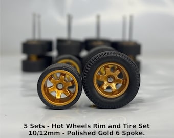 Peut inclure: Cinq ensembles de jantes et pneus Hot Wheels en or poli à 6 branches de 10/12 mm. Les pneus sont noirs et les jantes sont dorées. Les jantes ont un design à 6 branches.  "Hot Wheels 1:64 Scale" et "5 Sets - Hot Wheels Rim and Tire Set 10/12mm - Polished Gold 6 Spoke." sont imprimés sur l'image.